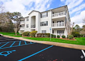 Thumbnail 4 of 23 - A row of white apartment buildings with green lawns in front.