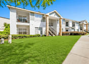 Thumbnail 4 of 23 - A row of white apartment buildings with green lawns in front.