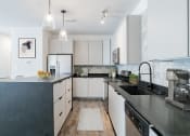 Thumbnail 25 of 46 - a modern kitchen with black counter tops and white cabinets at The Mobile Lofts, Mobile, 36604