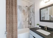 Thumbnail 29 of 46 - a bathroom with a sink and a shower and a mirror at The Mobile Lofts, Mobile, AL, 36604