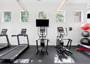 Thumbnail 10 of 23 - A gym with treadmills, elliptical machines, and a weight bench.