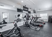 Thumbnail 9 of 23 - A gym with treadmills, exercise bikes, and a television.