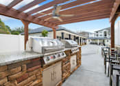 Thumbnail 7 of 19 - An outdoor kitchen with a grill and a fan.