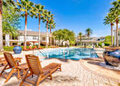 Thumbnail 12 of 23 - A pool surrounded by palm trees and wooden chairs.