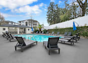 Thumbnail 6 of 19 - A pool surrounded by lounge chairs and a white fence.