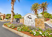 Thumbnail 18 of 23 - A sign for Villas Bon Secour sits in front of a flower bed.