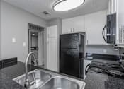 Thumbnail 45 of 47 - A kitchen with a black fridge and stove top oven.