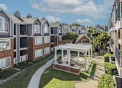 Thumbnail 8 of 47 - A sunny day at a residential complex with apartment buildings and a central courtyard.
