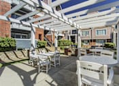 Thumbnail 13 of 47 - A white patio with a table and chairs under a pergola.