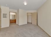 Thumbnail 21 of 46 - a spacious living room with white walls and carpet and a door to a bathroom