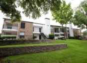Thumbnail 42 of 47 - exterior view of apartments with a green lawn and stone retaining wall