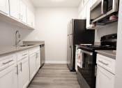 Thumbnail 26 of 47 - a kitchen with white cabinets and a black stove and refrigerator
