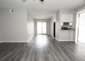 Thumbnail 11 of 47 - an empty living room with wood floors and a kitchen