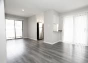 Thumbnail 27 of 47 - an empty living room with wood floors and a refrigerator
