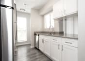 Thumbnail 23 of 47 - an empty kitchen with white cabinets and a stainless steel refrigerator