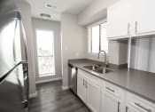 Thumbnail 25 of 47 - an empty kitchen with white cabinets and a stainless steel sink