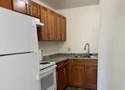 Thumbnail 15 of 24 - A kitchen with a white fridge and wooden cabinets.