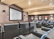 Thumbnail 17 of 70 - A home theater with a row of seats and a large screen.