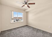 Thumbnail 44 of 70 - A room with a ceiling fan and a window overlooking a residential area.
