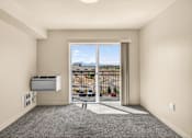 Thumbnail 54 of 70 - A room with a sliding glass door leading to a balcony with a view of the city.