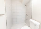 Thumbnail 21 of 23 - A white bathroom with a toilet, tub, and shower.