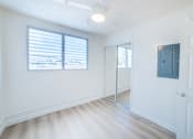 Thumbnail 14 of 23 - A room with a white door, a mirror, and a window with blinds.