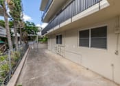 Thumbnail 6 of 23 - A concrete patio is surrounded by a building and trees.