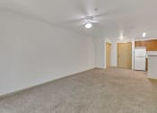 Thumbnail 29 of 46 - an empty living room with a kitchen and a ceiling fan