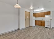 Thumbnail 42 of 46 - the living room and kitchen of an apartment with wood flooring and white appliances