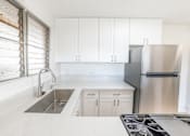 Thumbnail 29 of 33 - A kitchen with white cabinets and a stainless steel refrigerator.