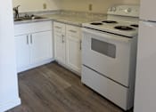 Thumbnail 9 of 24 - A white kitchen with a stove, sink, and cabinets.