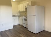 Thumbnail 10 of 24 - A white refrigerator in a kitchen with wooden floors.