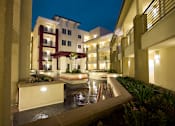 Thumbnail 5 of 5 - A building with a pool in front of it at night.