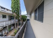 Thumbnail 7 of 23 - A balcony with a white wall and a tree in the background.