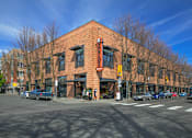 Thumbnail 1 of 25 - A red brick building with a yellow awning sits at a street corner.