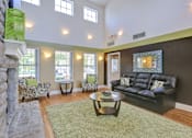 Thumbnail 6 of 21 - A living room with a black couch and a fireplace.