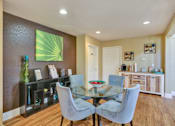 Thumbnail 8 of 21 - A dining room with a glass table and grey chairs.