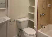 Thumbnail 12 of 13 - A white toilet sits next to a sink in a small bathroom.