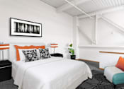 Thumbnail 17 of 25 - A bedroom with a white bed and a black and white picture on the wall.