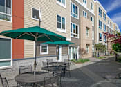 Thumbnail 6 of 25 - A patio with a table and chairs and an umbrella.