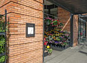 Thumbnail 3 of 25 - A brick wall with a plaque and a hanging flower basket.