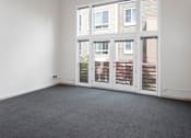 Thumbnail 15 of 25 - A room with a grey carpet and a white wall with a window.
