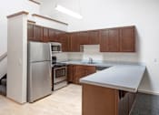 Thumbnail 14 of 25 - A kitchen with wooden cabinets and a stainless steel refrigerator.