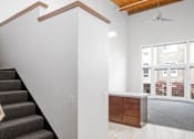 Thumbnail 19 of 25 - A staircase with a wooden handrail leads to a room with a ceiling fan and a window overlooking a balcony.