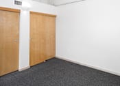 Thumbnail 24 of 25 - Two brown doors in a white room with grey carpet.