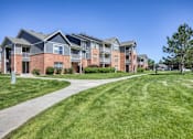 Thumbnail 2 of 20 - A row of apartment buildings with a grassy area in front.