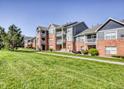 Thumbnail 1 of 20 - A row of modern brick apartment buildings with green lawns in front.