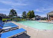 Thumbnail 9 of 20 - A pool area with blue loungers and a clear sky.