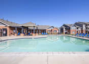 Thumbnail 10 of 20 - A large swimming pool in front of a building with lounge chairs around it.