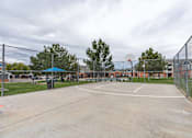 Thumbnail 8 of 20 - A basketball court is surrounded by a chain link fence.